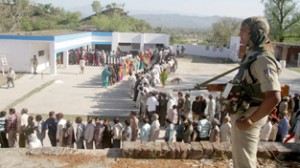 A para-military jawan guards a polling station with large queue of voters at Bajalta in Nagrota on Thursday. —Excelsior/Rakesh