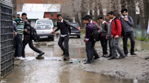 Boys use bricks to cross a water logged road in Baramulla on Monday. -Excelsior/Abid Nabi