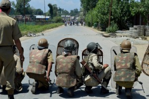 Security personnel and police take cover behind shields as youths pelt stones on them in Kulgam on Monday. -Excelsior/Sajad Dar