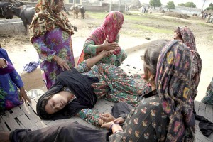 A woman collapsed as others help her after killings and destruction of property in Pakistan shelling at Jeora Farm in R S Pura sector on Saturday. More pics on page 5.—Excelsior/Rakesh