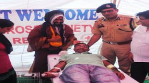 A youth donating blood in the presence of Shri Balak Yogeshwar Dass Ji and SSP Jammu, Uttam Chand during a blood donation camp at Jammu.