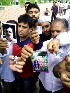 People showing photograph of their family members, who are trapped in Srinagar, outside Technical Airport at Jammu. -Excelsior/Rakesh