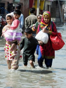People walk through flood hit area of Bemina in Srinagar carrying essential commodities on Friday. —Excelsior/Amin War