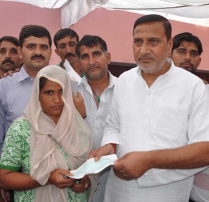 Minister for PHE, Sham Lal Sharma handing over a relief cheque to a flood affected victim.