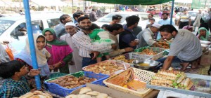 Few flood- affected shoppers buy festive sweets at an outdoor market ahead of the Eid-ul-Azha in South Kashmir’s Pulwama district, on Sunday. —Excelsior/ Younis Khaliq