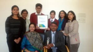 Students along with School authorities displaying British Council International School Award certificate while posing for a group photograph.