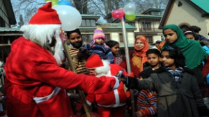 A man dressed as Santa Claus offering sweets to children during Christmas celebrations at the Holy Family Catholic Church in Srinagar, on Thursday. -Excelsior/Amin War