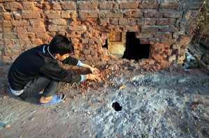 A youth sits near roof and wall of a house damaged in Pakistan shelling in Arnia town. More pics on page 3. — Excelsior / Rakesh