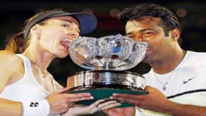 Martina Hingis of Switzerland and Leander Paes of India bite their trophy after defeating Kristina Mladenovic of France and Daniel Nestor of Canada to win their mixed doubles final match at the Australian Open 2015 Tennis Tournament in Melbourne. (UNI)