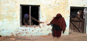 Women point towards their wall hit by bullets and splinters of mortar shells in Jora Farm in R S Pura sector on Monday. Excelsior/Rakesh