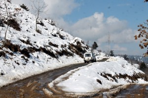 A vehicle moves in snow filled road at Zawoora in Shopian on Wednesday. -Excelsior/Younis Khaliq