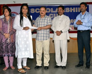 Divisional Commissioner Pawan Kotwal awarding a student during scholarship Award ceremony.