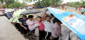 Yatris taking refuge under polythene sheets to save themselves from rain at Jammu Haat registration counter on Friday. -Excelsior/Rakesh