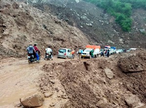 Vehicles crossing landslide hit stretch of highway at Kheri on Sunday.