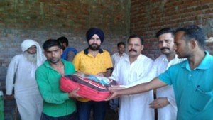 JKNPP president, Balwant Singh Mankotia, giving blanket to a landslide hit person at Uchha Pind Panchayat in Kathua district.