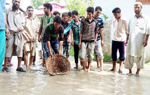 People drop fish in watery potholes as mark of protest against dilapidated condition of road in Panzgam area of Bandipora district. —Excelsior/ Aabid Nabi