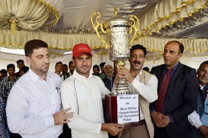 MLA Tangmarg Abas presenting title trophy of cricket tourney to winning team at Pattan on Tuesday.