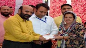 Minister for Social Welfare Bali Bhagat handing over a cheque to a beneficiary at Seri Panditan on Tuesday.