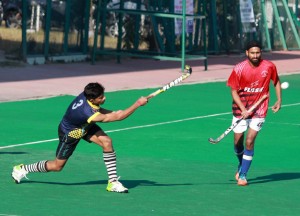 Player scooping the ball while another player watches during a hockey match at KK Hakhu Astroturf Stadium in Jammu on Saturday.— Excelsior/Rakesh