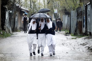 Students walk under the cover of umbrella as rains lash Kashmir on Friday. —Excelsior/Sajad Dar